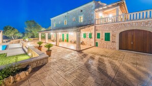 Un ampio cortile con piscina, pareti in pietra e un'area relax coperta.