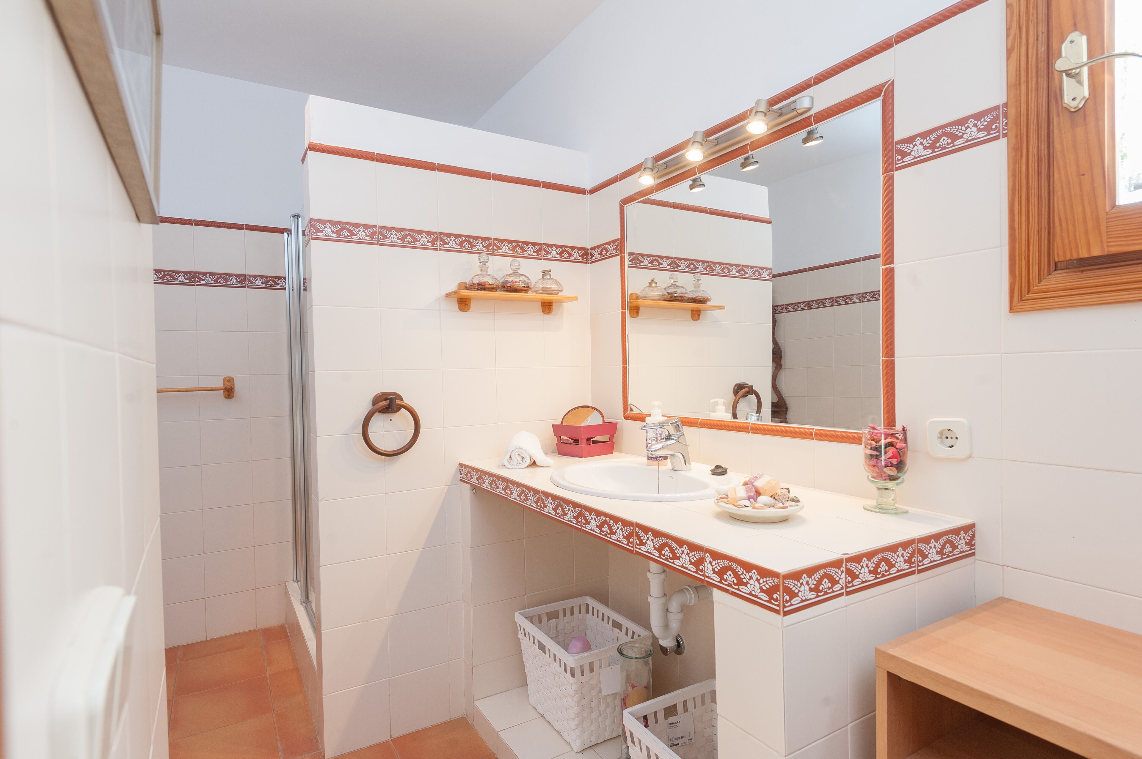 A bathroom with a white sink, mirror, and towel rack. There is a shower area with a glass door and a white basket.