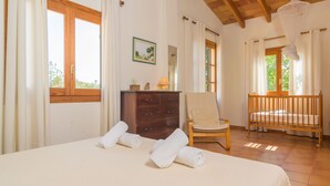 Une chambre à coucher avec un lit, une commode en bois, une chaise et un berceau.