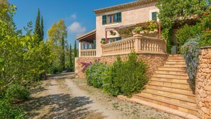 Une maison à deux étages avec un escalier en pierre menant à un balcon.