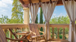 Un balcon avec deux chaises à rayures, une petite table et un pot de fleurs.