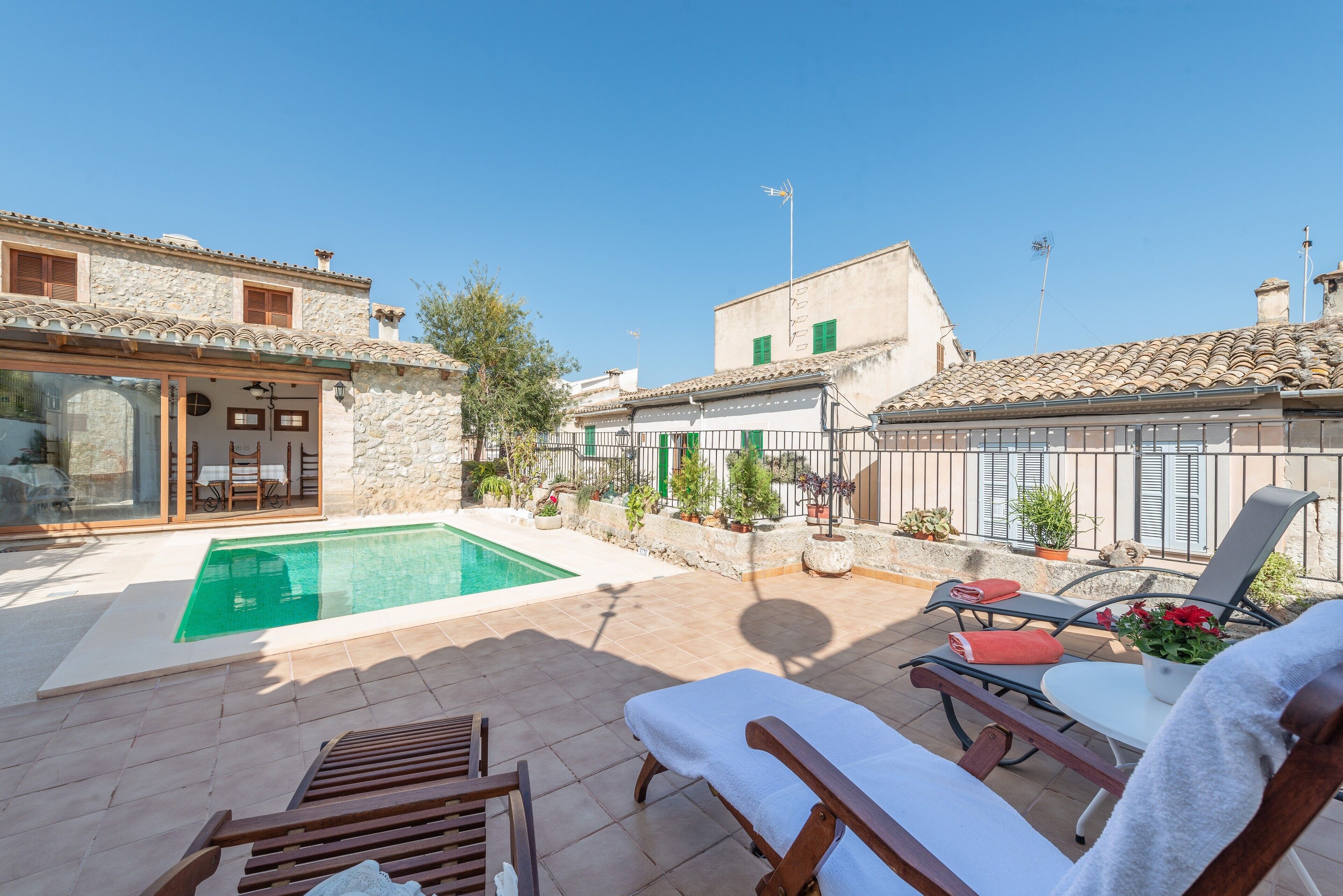 A poolside area with lounge chairs, a small pool, and potted plants.