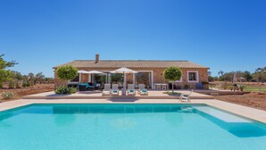 Et hus med swimmingpool, udendørs siddepladser og en patio.
