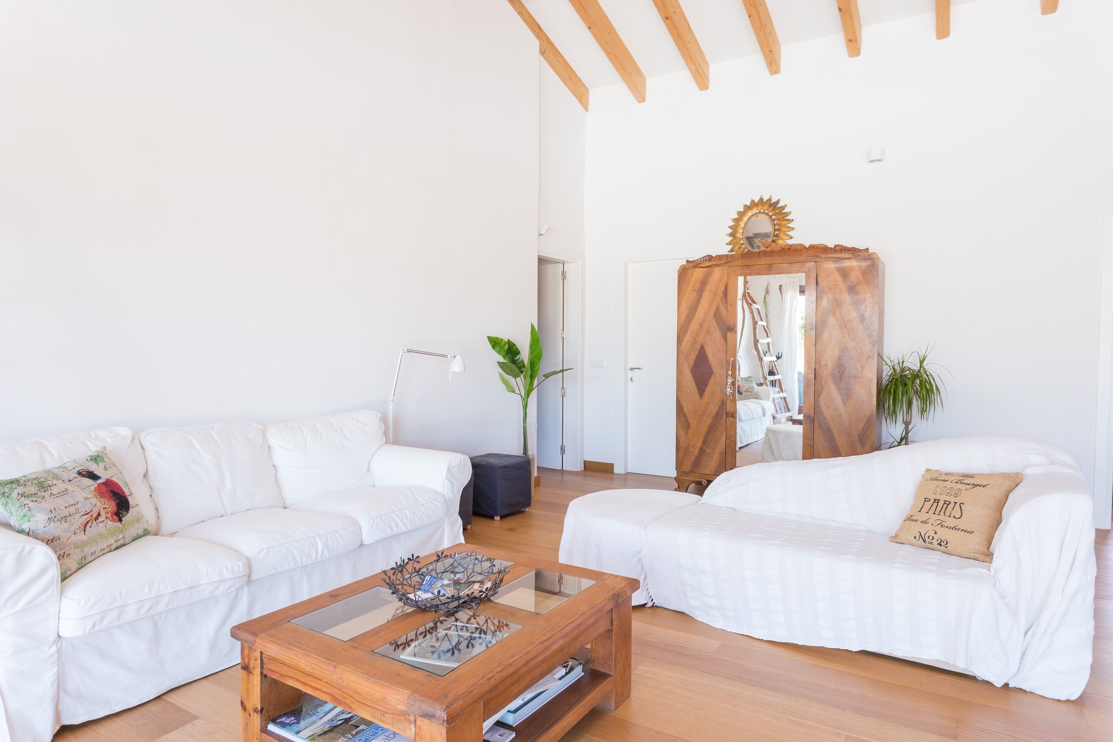 Una sala moderna con dos sofás blancos, una mesa de centro de madera y un aparador de madera con espejo.