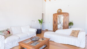 En moderne stue med to hvide sofaer, et træsofabord og et skab med et spejl.