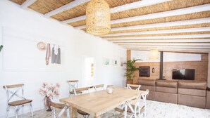 A spacious living area with a wooden dining table and chairs, a sofa, and a TV mounted on a brick wall. - CAN JOAN DES FORN - House with private pool in Inca. Free WiFi (Inca)