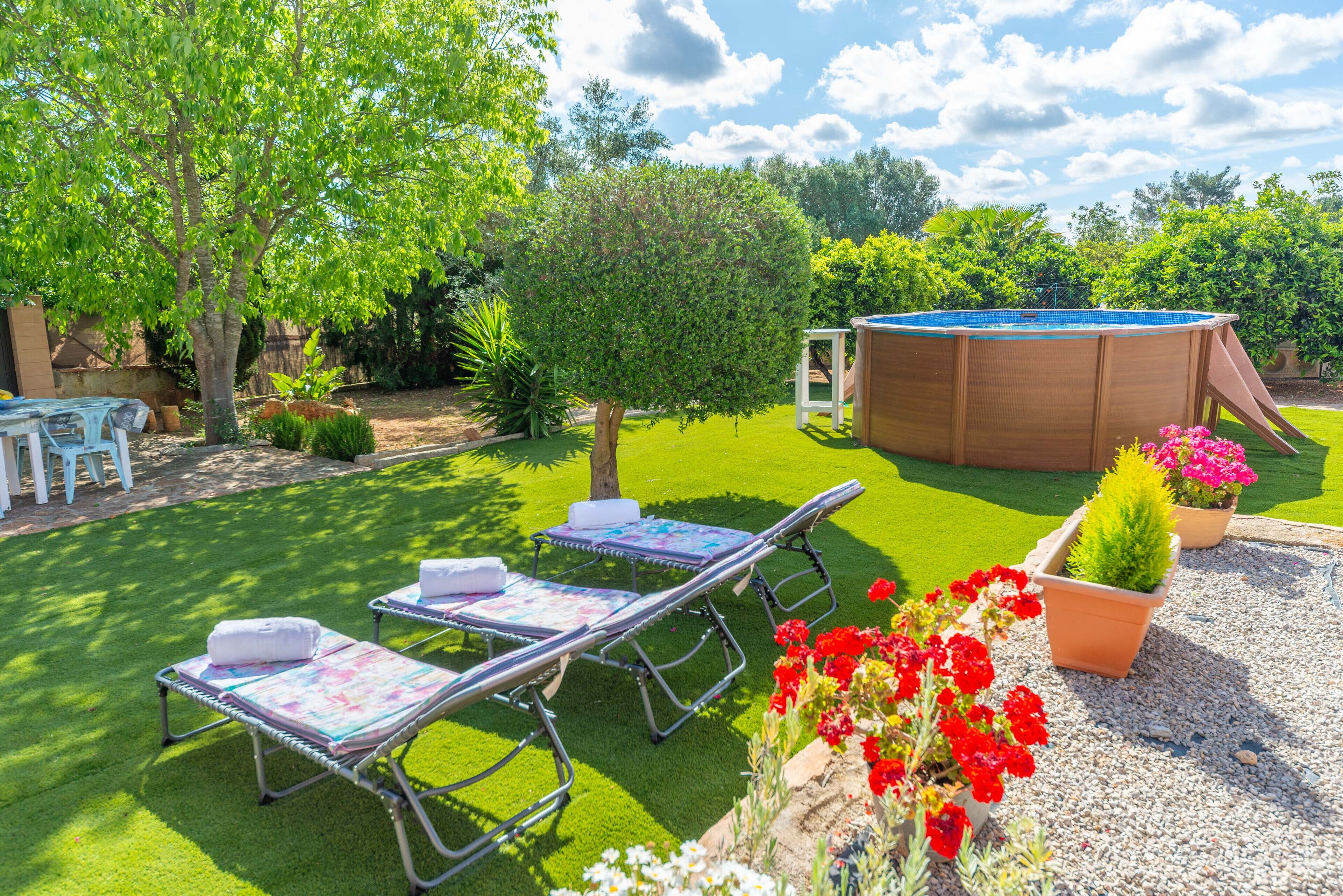 Patio trasero con jacuzzi, sillas de descanso y un área de juegos pequeña.