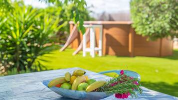 Een tafel met een fruitschaal en een bloevas in een tuin.