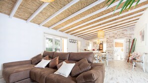 A spacious living room with a large brown sectional sofa, a wooden ceiling, and a white brick wall. - CAN JOAN DES FORN - House with private pool in Inca. Free WiFi (Inca)