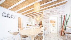A spacious dining area with a wooden table and chairs, a hanging light fixture, and a brick wall. - CAN JOAN DES FORN - House with private pool in Inca. Free WiFi (Inca)