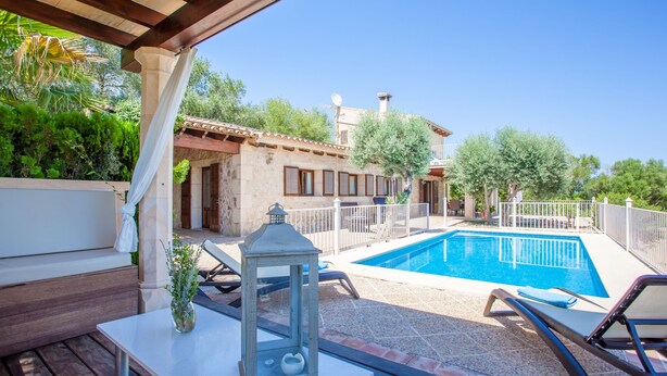 Ein Poolbereich mit einer Pergola, Liegestühlen und einer Laterne.