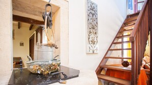 Ein rustikaler Innenraum mit einer Steinarbeitsplatte, einer hängenden Seils und einer Holztreppe.