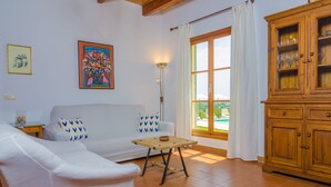 A living room with a sofa, a small wooden table, a cabinet, and a painting on the wall. - SON MORA - Villa with private pool in Porreres. Free WiFi (Porreres)