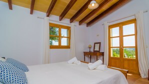 A bedroom with a large bed, two windows, a bedside table, and a bench. - SON MORA - Villa with private pool in Porreres. Free WiFi (Porreres)