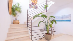 Un escalier avec une rampe en métal, une plante en pot et un tableau accroché au mur.