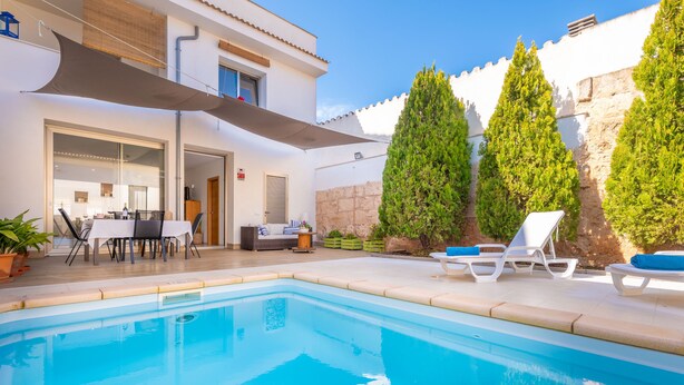 Une piscine avec des chaises longues et un espace repas aménagé avec du mobilier d’extérieur.