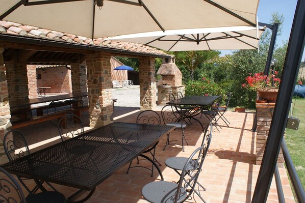 An outdoor patio with brick tables and chairs, a barbecue grill, and a stone oven.