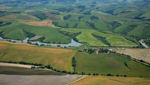 Vista panorâmica de colinas ondulantes, uma pequena aldeia e campos.