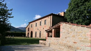 Ein Gebäude aus Stein mit Innenhof, Bogenportalen und Bergblick im Hintergrund.