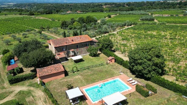 Eine Villa mit Schwimmbad, umgeben von Weinbergen und einem Steinhäuschen.