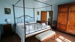 Ein Himmelbett mit einer Bank, ein Holzschrank und zwei Nachttische mit Lampen.