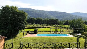 Ein Garten mit Schwimmbad, einer Pergola und Blick auf ein Gebirge.