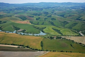A panoramic view of rolling hills with a small village and fields.