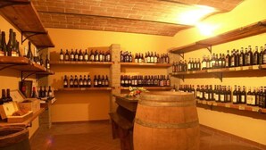 A wine cellar with shelves stocked with wine bottles, a wooden barrel, and a brick ceiling. - Cosy apartment in villa for 6 people with pool, WIFI, patio and panoramic view (Peccioli)