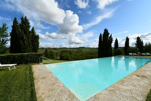 Relax by the serene pool surrounded by lush greenery and rolling hills.