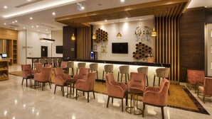 A modern bar area with a counter, seating, and a TV screen. - Hilton Garden Inn Isparta (Isparta)