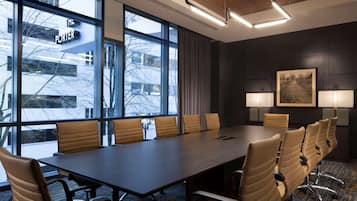 A conference room with a long table, multiple chairs, and large windows.