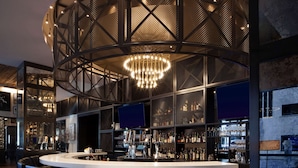 Zona de bar moderna amb barra circular, diverses opcions de seients i un penjall decoratiu.