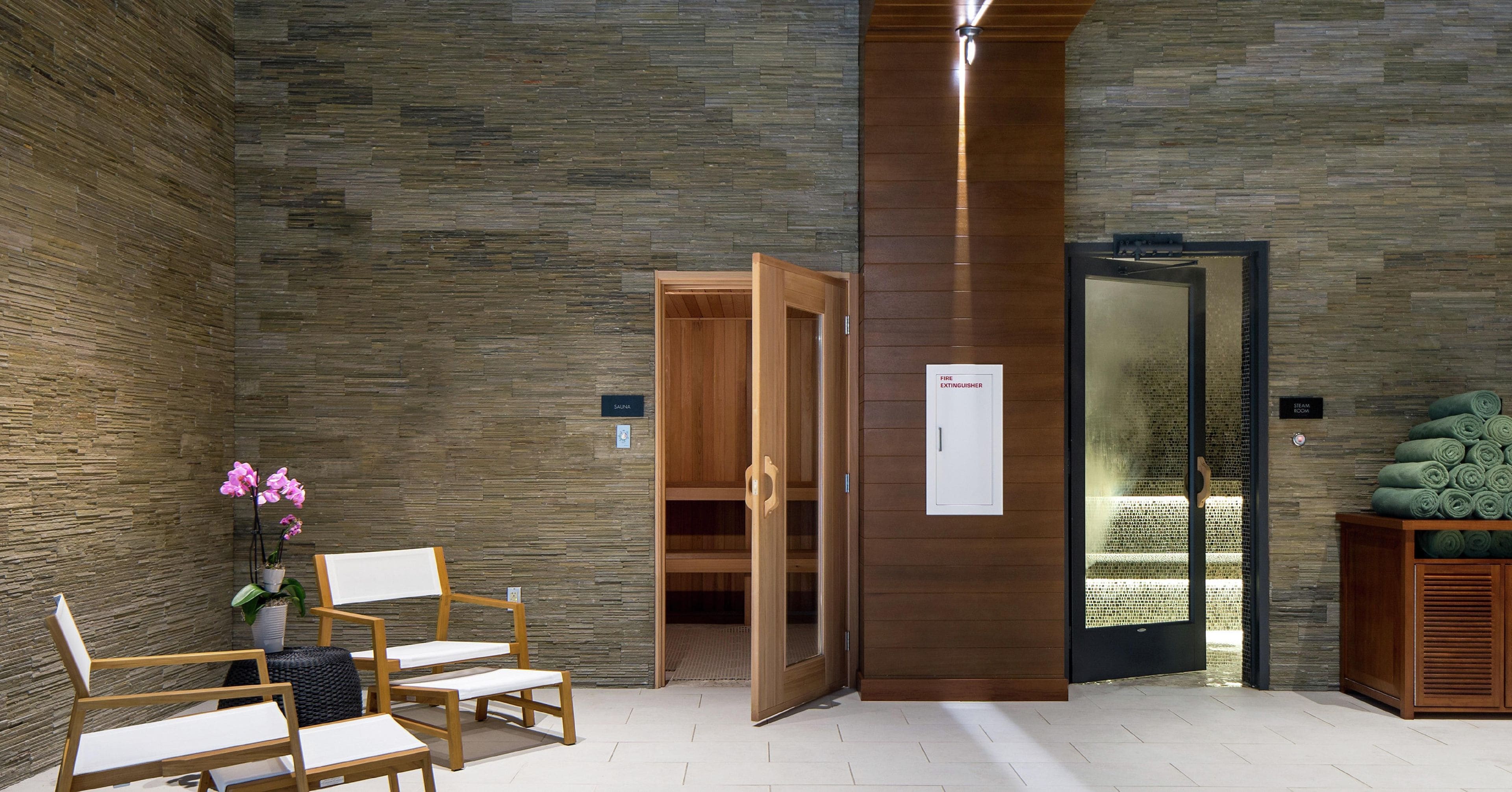 A spa area with wooden chairs, a sauna door, and a steam room door.