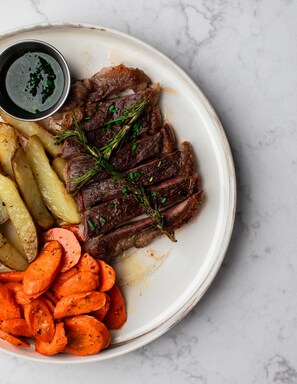 A plate of sliced beef, roasted potatoes, and carrots. - The Porter Portland, Curio Collection by Hilton (Portland)