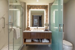 A modern bathroom with a glass shower enclosure, a wooden vanity with a mirror, and a toilet.
