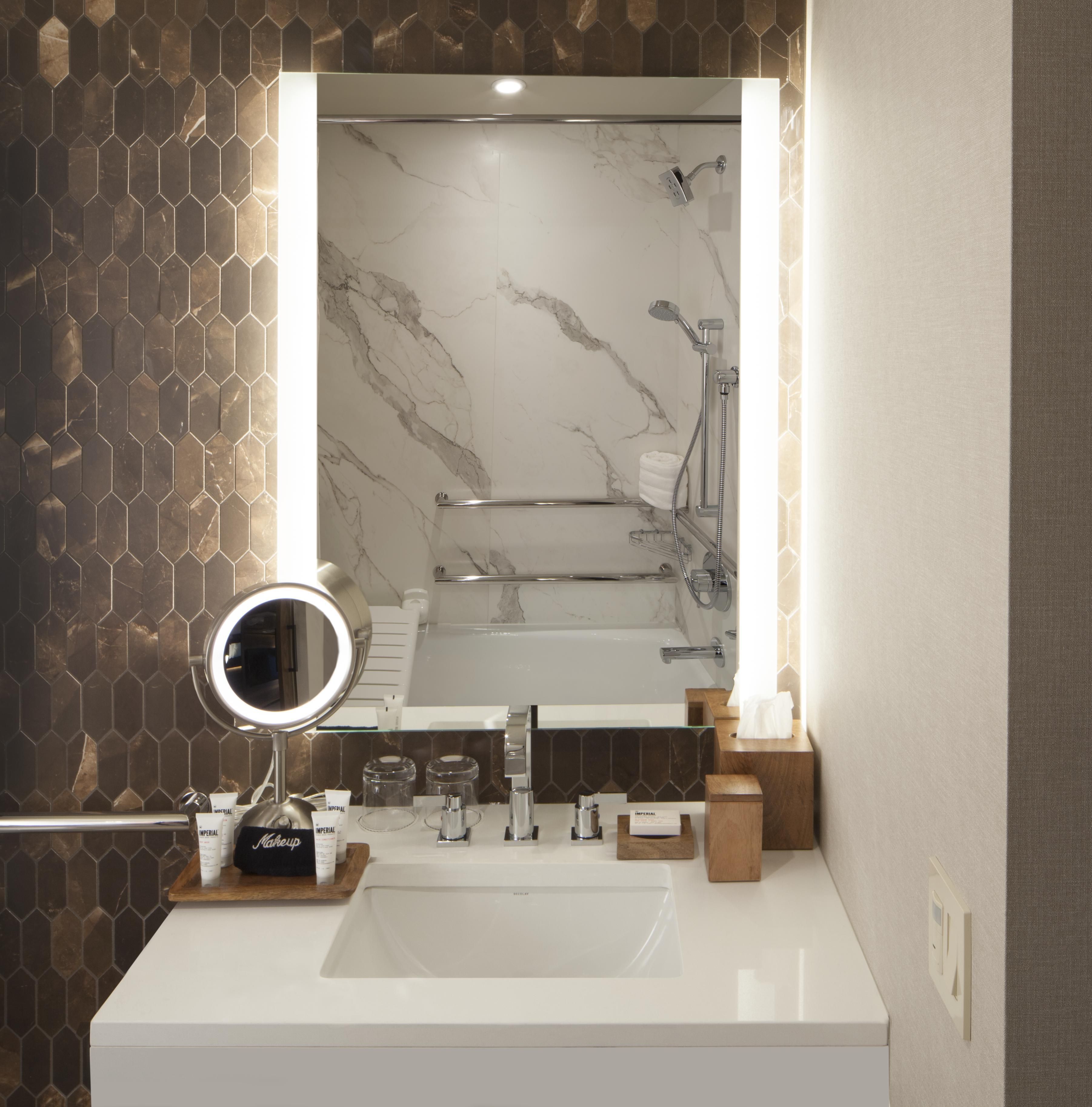 A bathroom with a white sink, a mirror, and a shower.