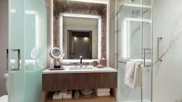 A modern bathroom with a glass-enclosed shower, a large mirror, and a wooden vanity.