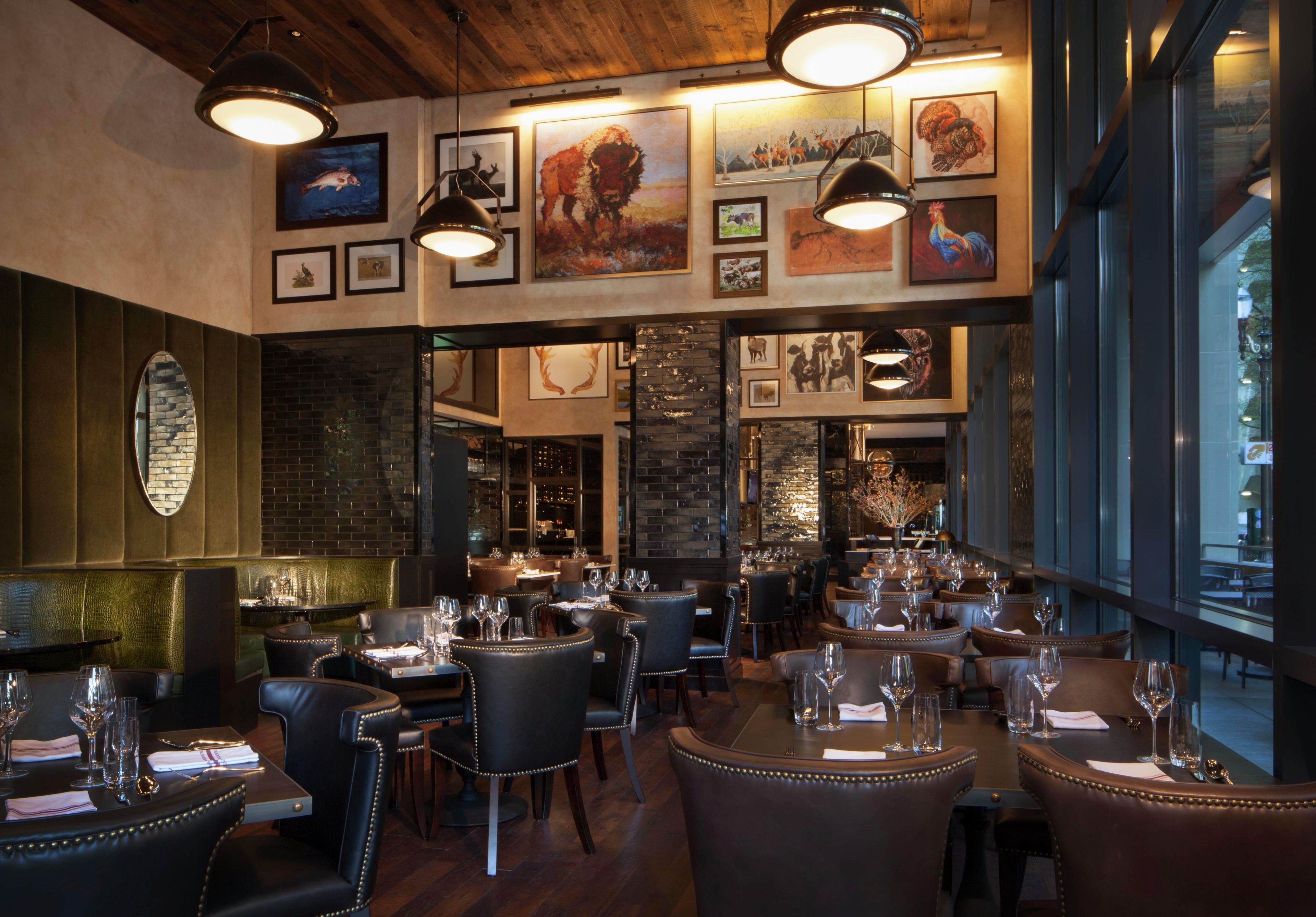 Un interior de restaurante con asientos de cuero, obras de arte enmarcadas en las paredes y una pared decorativa de ladrillo.