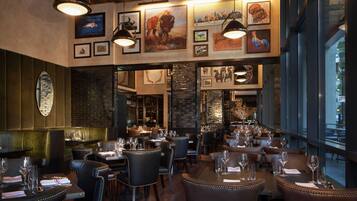 Un interior de restaurante con asientos de cuero, obras de arte enmarcadas en las paredes y una pared decorativa de ladrillo.