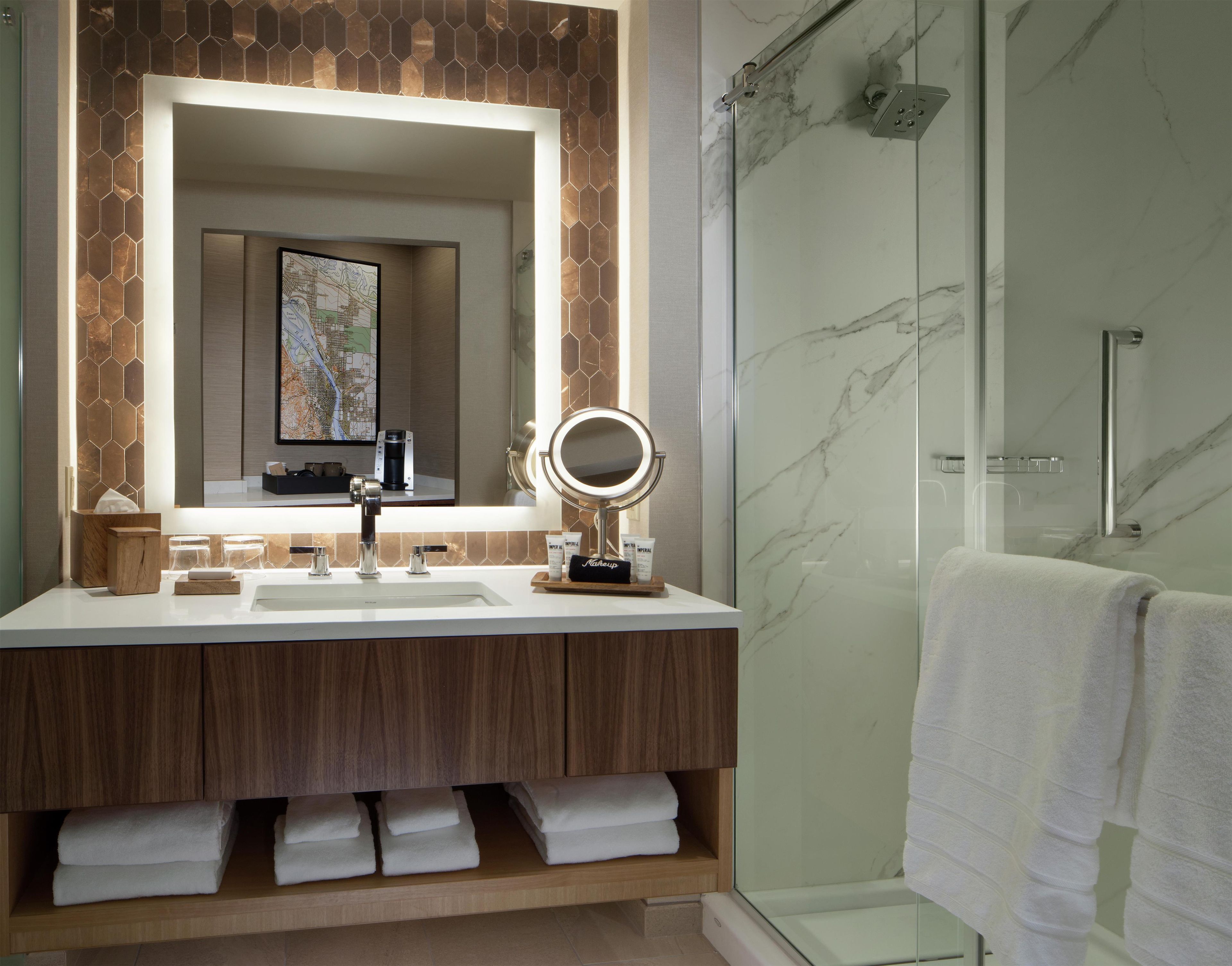 Une salle de bain avec un grand miroir, un lavabo et une douche.
