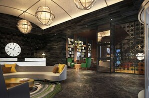 A modern lobby with a curved sofa, green chairs, a large bookshelf, and a clock on the wall.