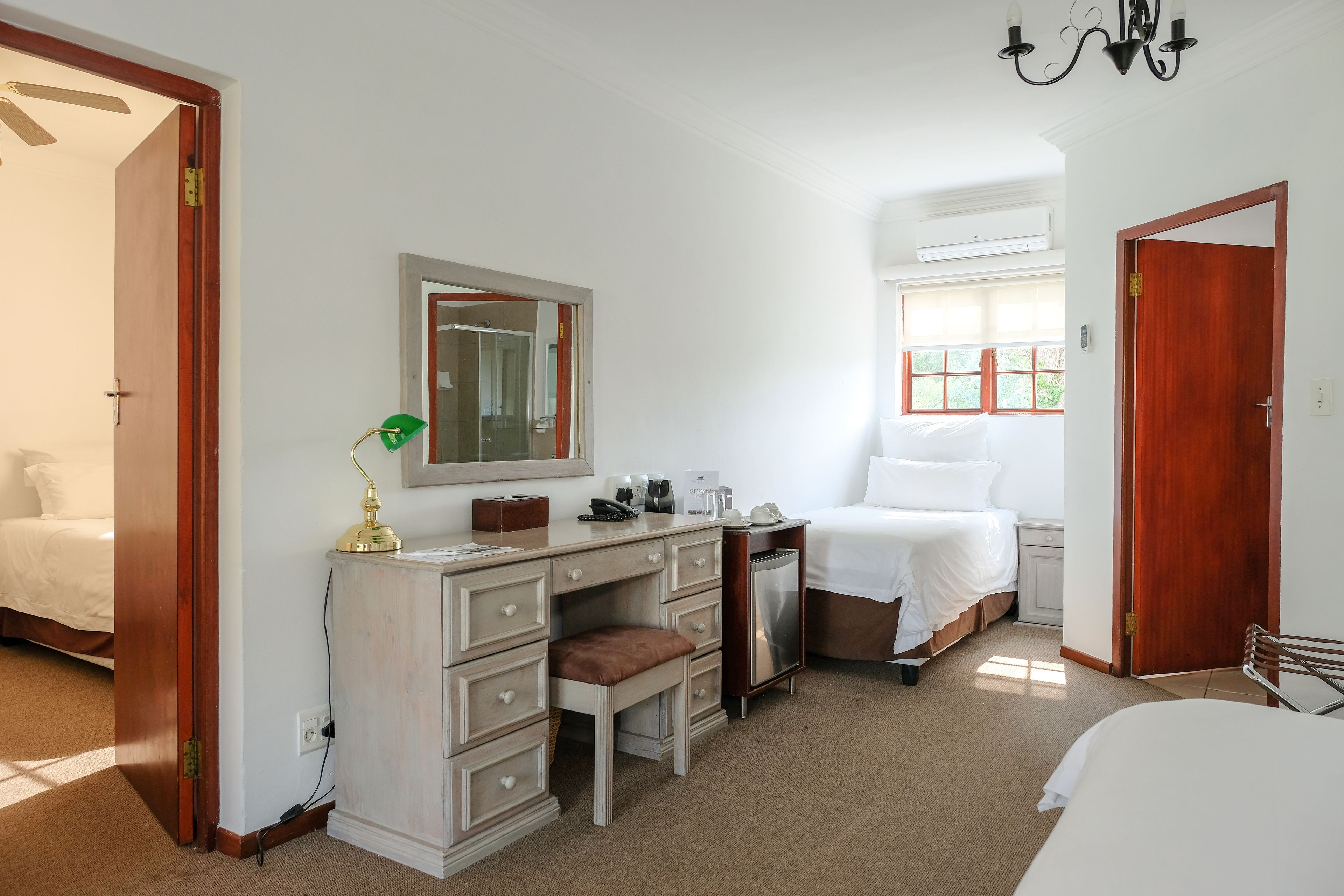 Een slaapkamer met een bed, een bureau met stoel, een dressoir en een spiegel.