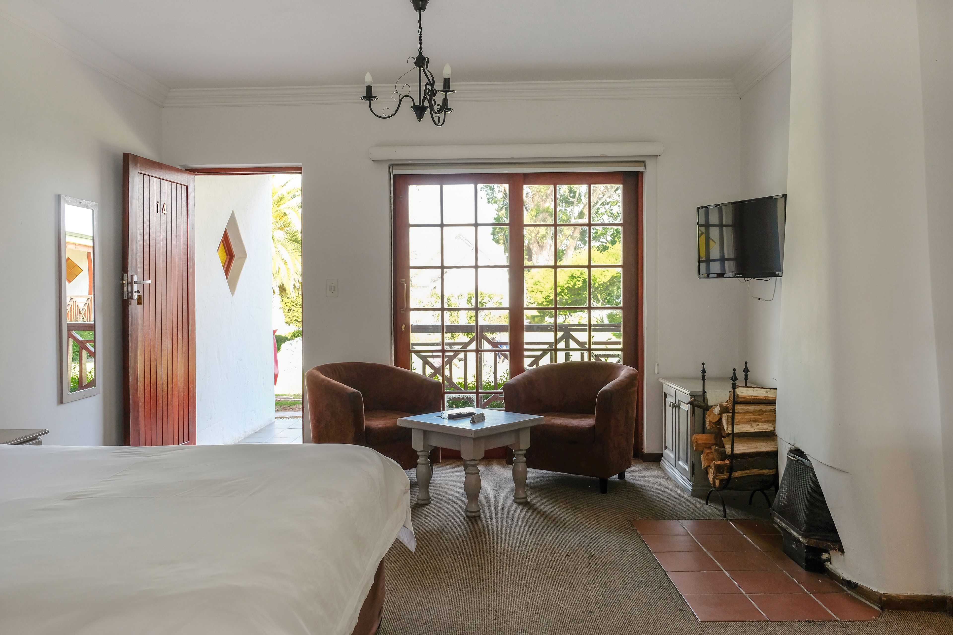 Un dormitorio con una cama, una mesa, dos sillones, un televisor y una chimenea.