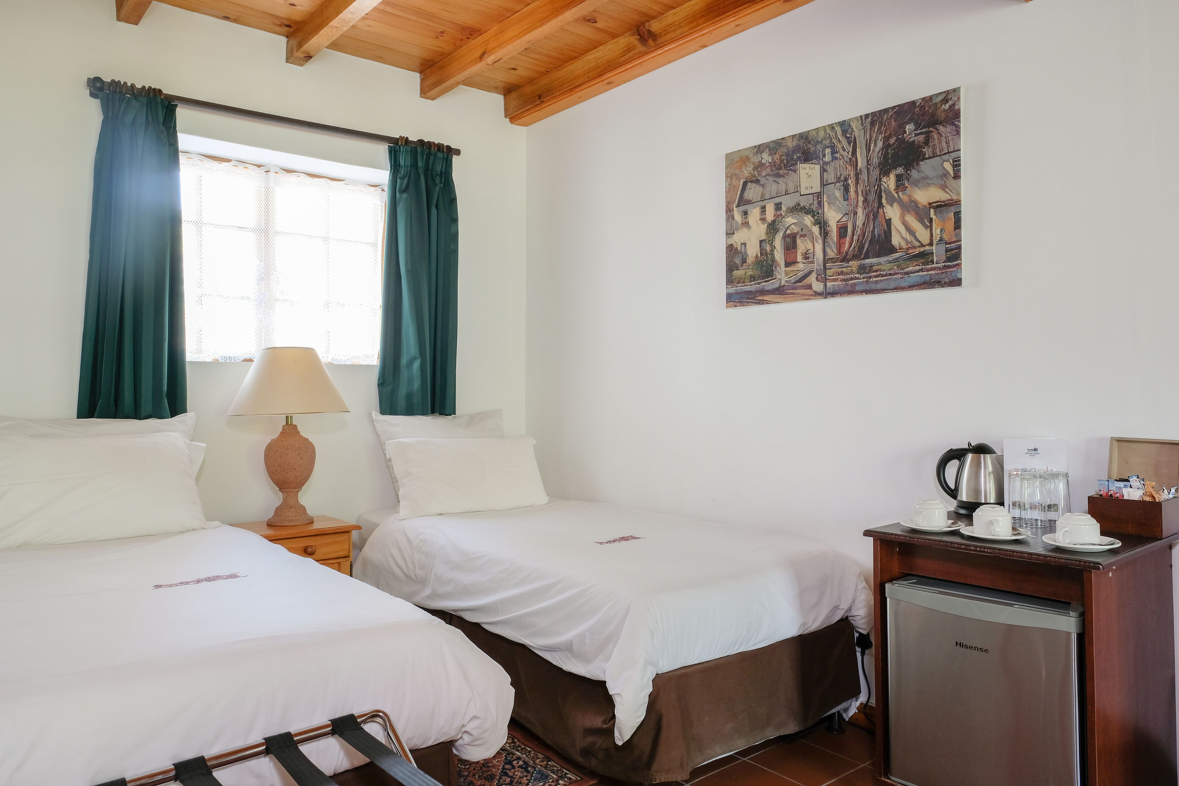 A hotel room with two beds, a desk with a coffee maker, and a refrigerator.