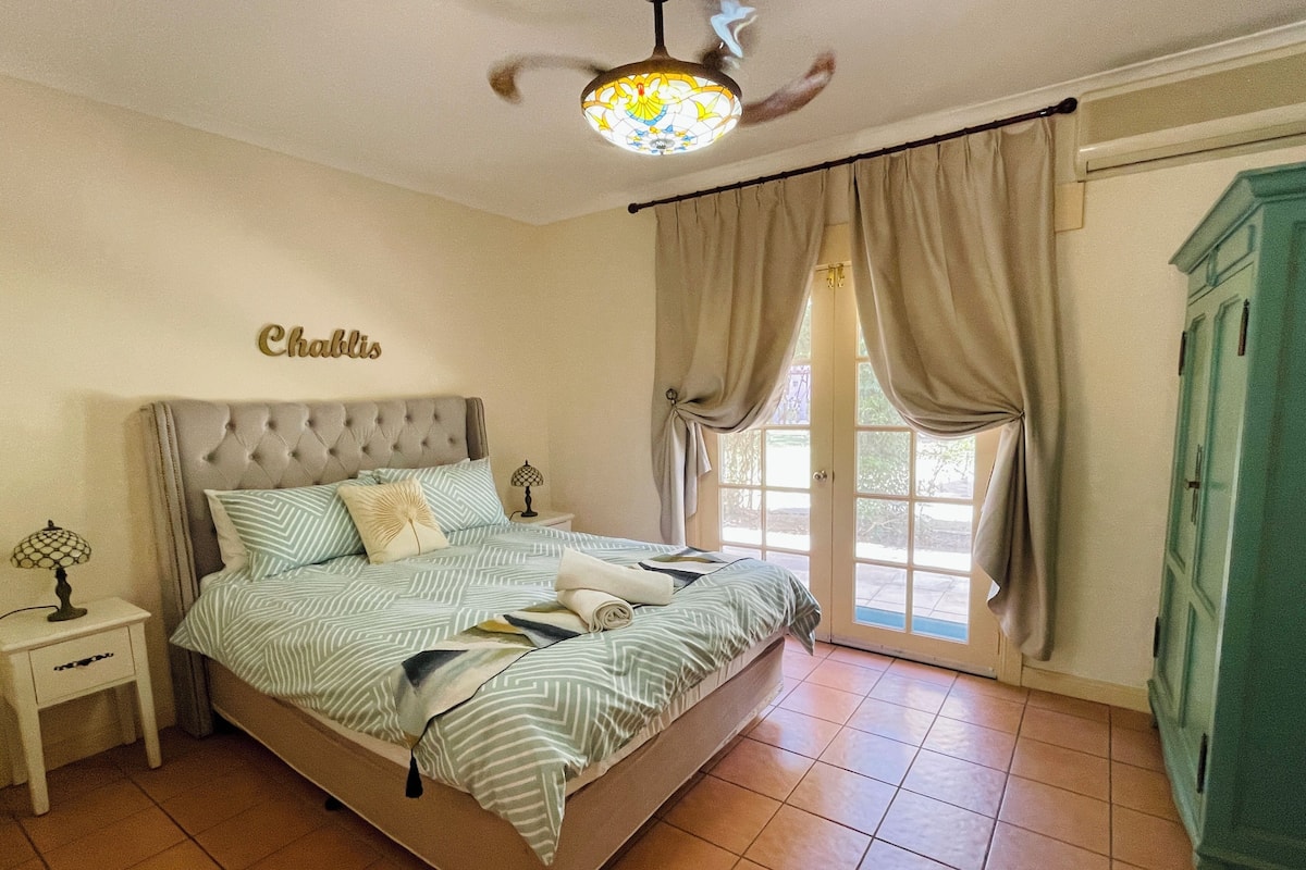 A bedroom with a bed, a nightstand, a lamp, a ceiling fan, and a wardrobe.