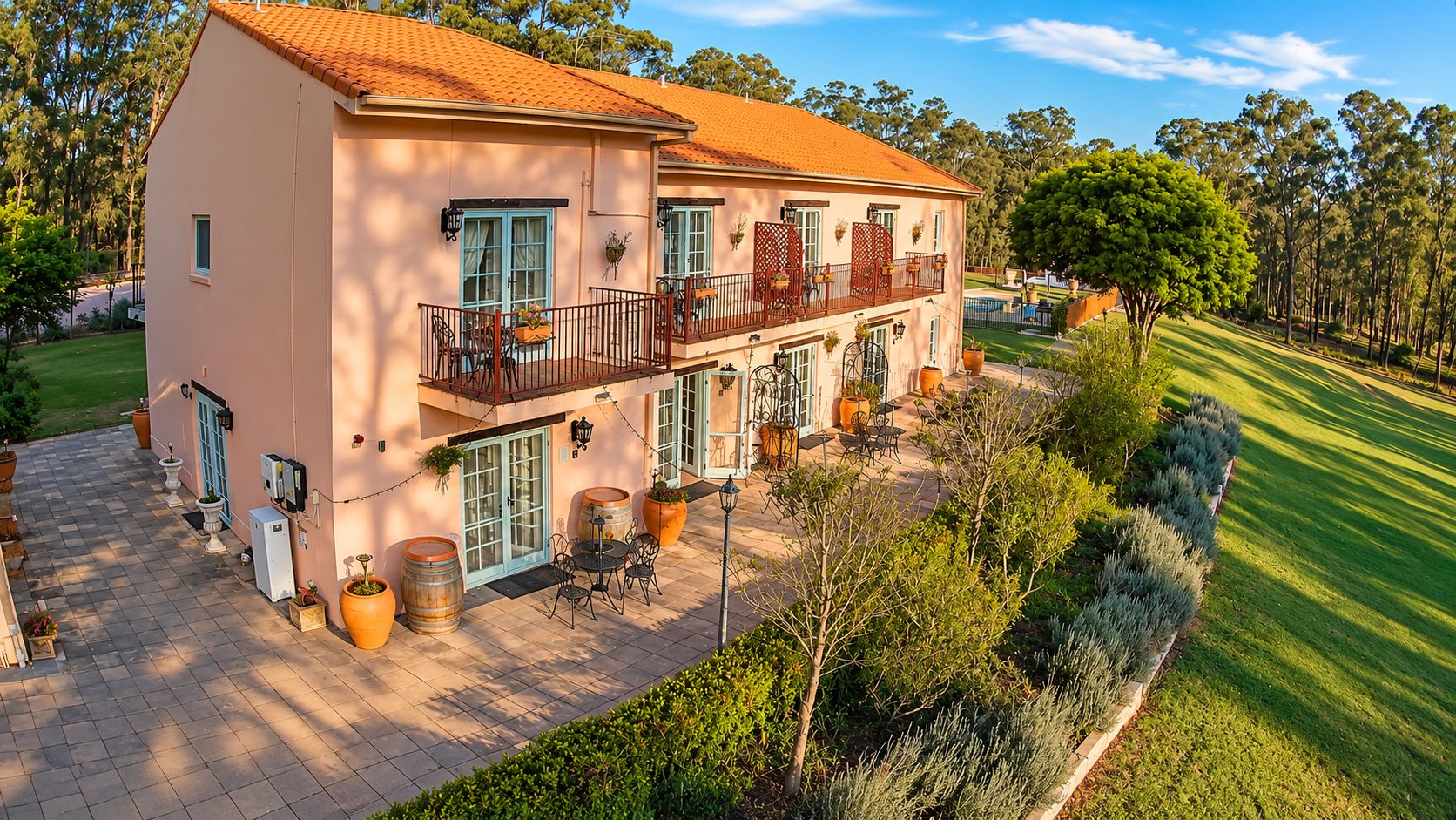 A two-story building with a balcony, outdoor seating, and a well-maintained lawn.