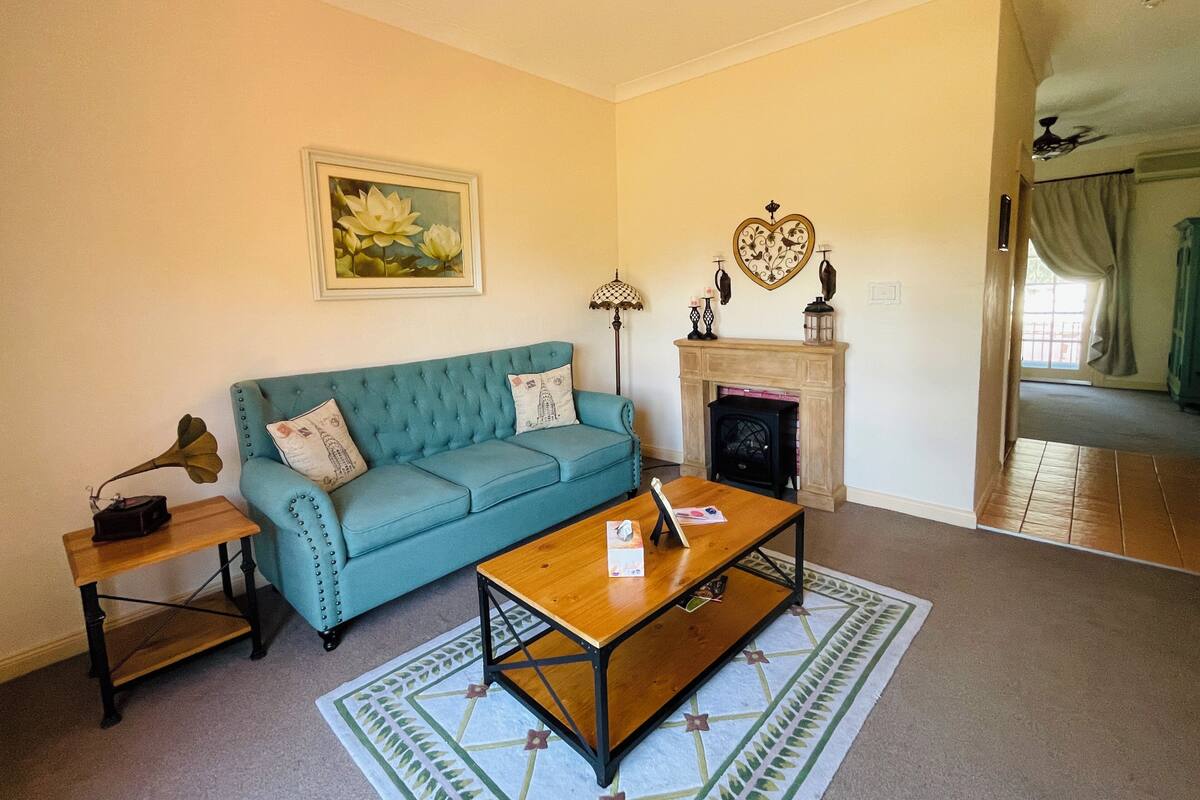 A living room with a blue sofa, a wooden coffee table, a fireplace, and a framed picture on the wall.