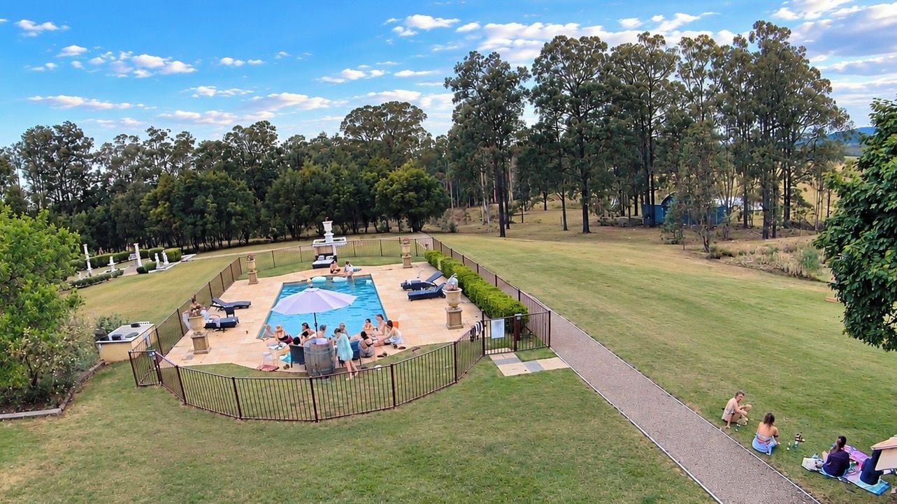 A backyard with a swimming pool, lounge chairs, and a fenced area.