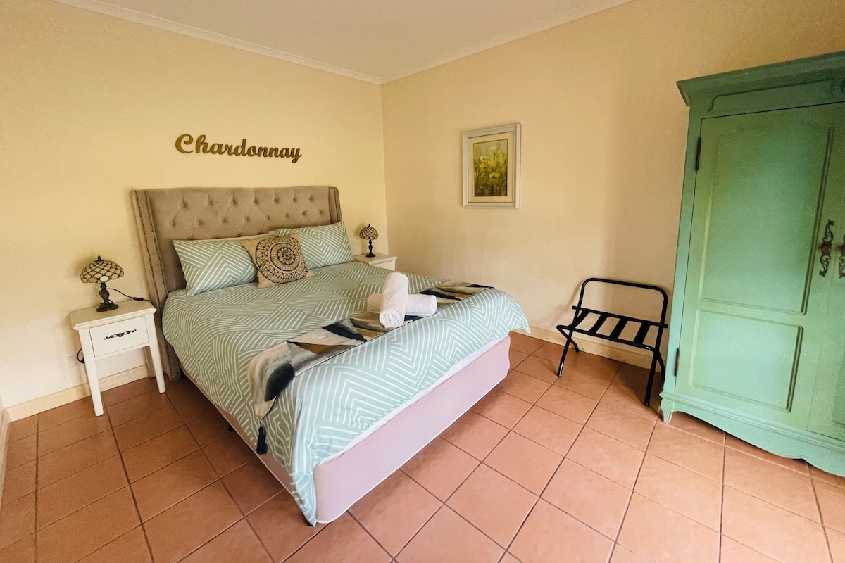 A bedroom with a bed, nightstands, a green wardrobe, and a wall sign.