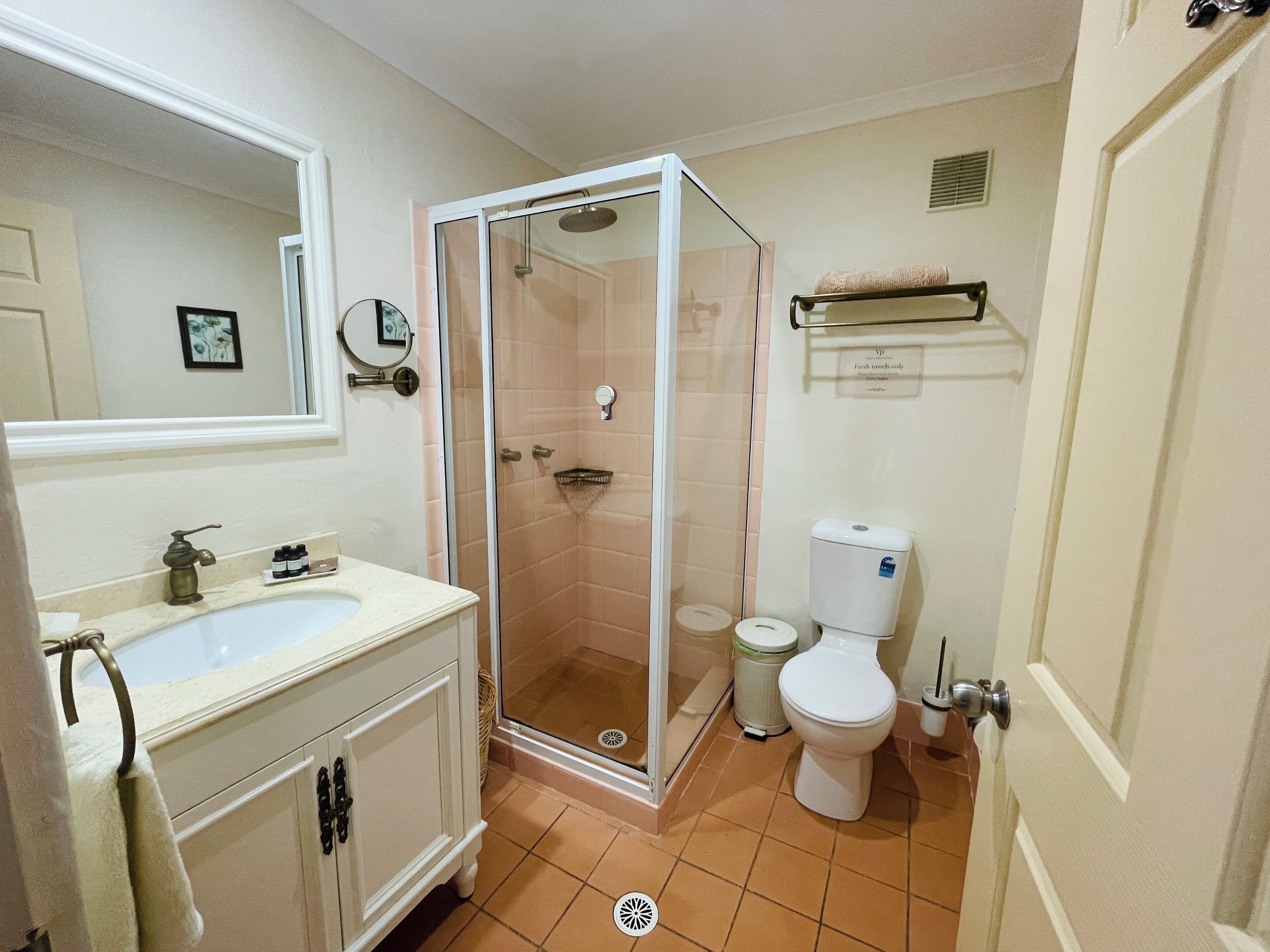 A bathroom with a shower enclosure, a toilet, and a sink.